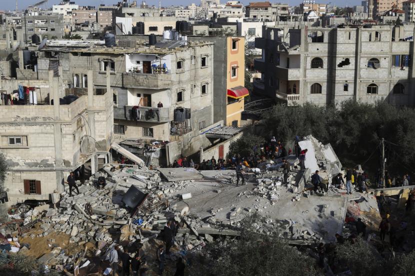 Warga Palestina menyaksikan kehancuran pasca serangan Israel terhadap sebuah bangunan tempat tinggal di Rafah, Jalur Gaza, Ahad, 3 Maret 2024. 