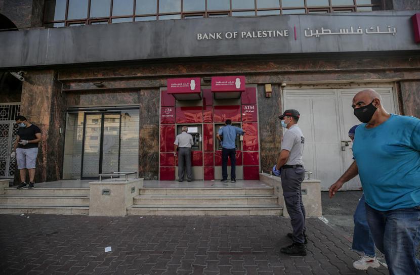Warga Palestina tampak mengenakan masker dan berdiri berjauhan saat antre mengambil uang di ATM, 31 Agustus 2020. 