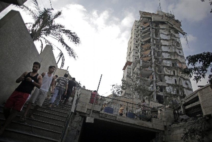Warga Palestina tengah berjalan di antara reruntuhan gedung yang hancur akibat serangan Israel. Usai gencatan senjata permanen diberlakukan, Qatar, negara pendukung Hamas, siap membangun kembali Gaza.