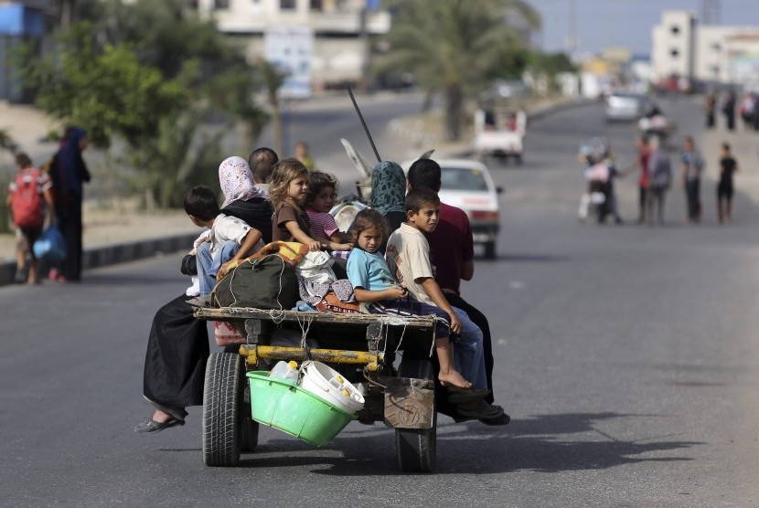 Warga Palestina yang tinggal di Gaza mengungsi menuju tempat perlindungan PBB, Ahad (13/7)