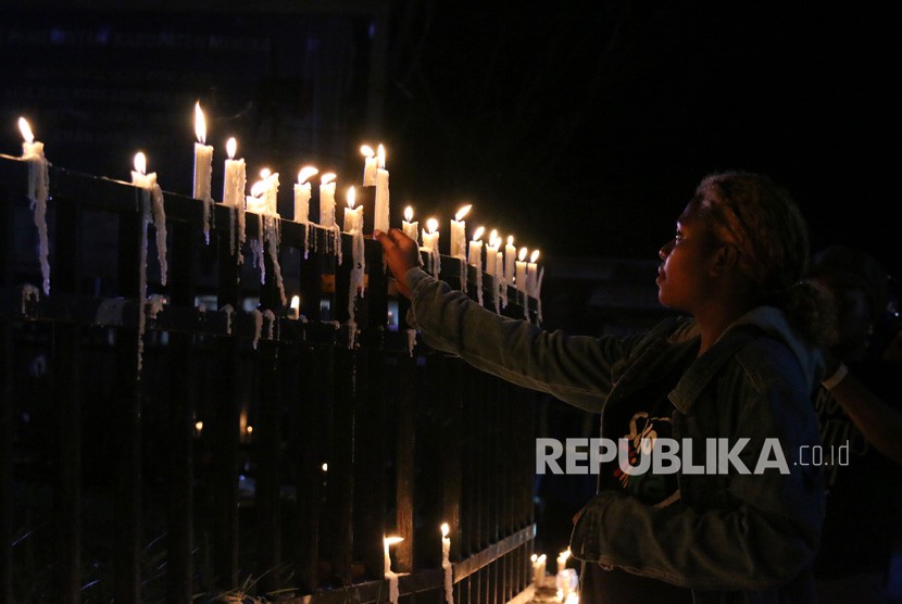 Warga Papua menyalakan lilin saat aksi damai di Bundaran Tugu Perdamaian Timika Indah, Mimika, Papua, Senin (19/8/2019).