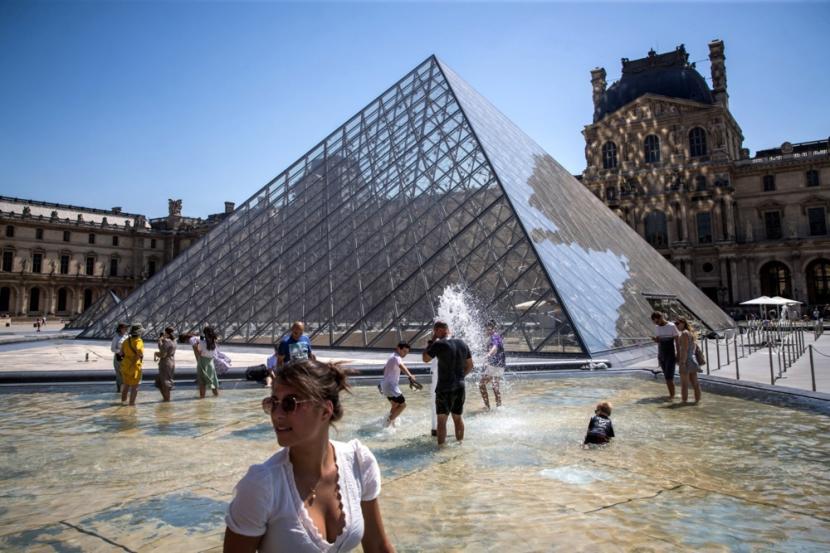 Warga Paris dan wisatawan bersantai di air mancur Piramida Museum Louvre di Paris, Prancis, 19 Juli 2022. Prancis menghadapi gelombang panas yang mempengaruhi seluruh negeri, bersamaan dengan kebakaran hutan, dengan suhu mencapai 40 derajat Celcius di seluruh wilayah.