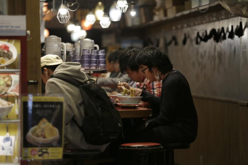  Warga saat makan di toko ramen kecil di distrik hiburan dekat stasiun Shibuya sebelum pemerintah memberlakukan penutupan pada jam 8malam untuk restoran dan bar di Tokyo, Jepang, Sabtu (25/4). Seluruh bisnis di Jepang perlahan dibuka kembali selama pandemi Covid-19. Ilustrasi. 