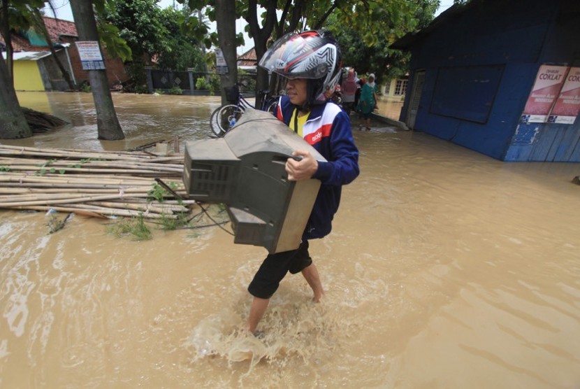 Warga sambil membawa barang melintasi banjir yang melanda desa Pilangsari, Kecamatan Jatibarang, Indramayu, Jawa Barat, Senin (16/3). Banjir akibat jebolnya tanggul sungai Cimanuk merendam sedikitnya 4 kecamatan di Indramayu.