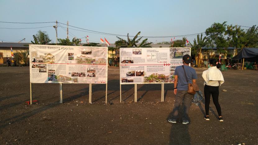 Warga sedang melihat papan informasi terkait pembangunan Kampung Akuarium, Kamis (20/8).