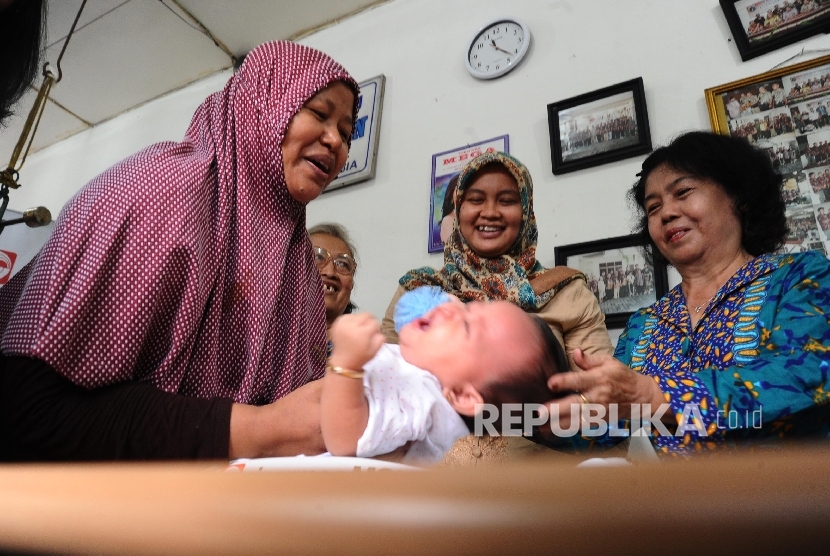  Warga sedang memeriksakan kesehatan anak bayinya di Posyandu Flamboyan, Pinangsia, Jakarta, Kamis (31/3). 