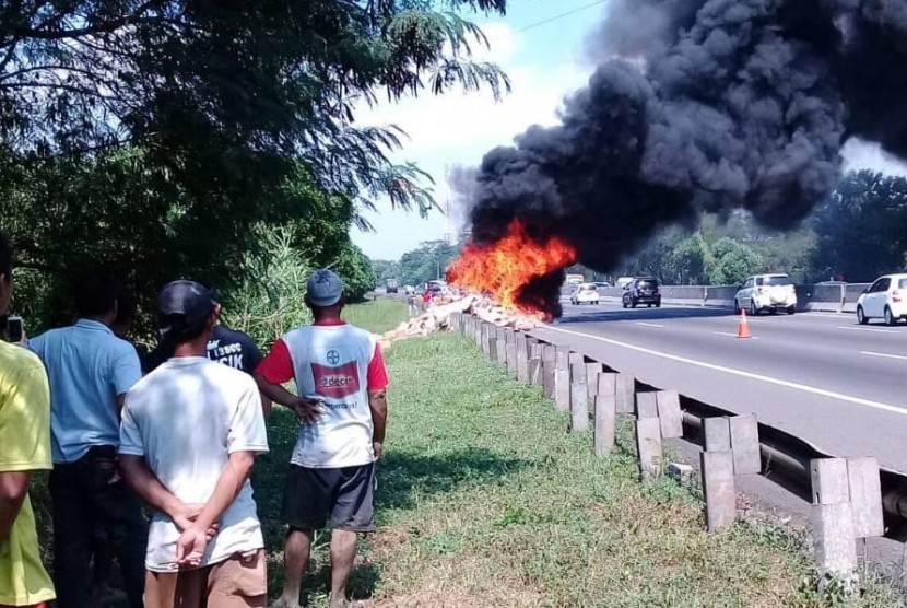 Warga sedang menyaksikan truk boks bermuatan sosis Nopol N 8547 RD, yang terbakar di ruas Tol Cipularang KM 86+400, Kecamatan Jatiluhur, Kabupaten Purwakarta.