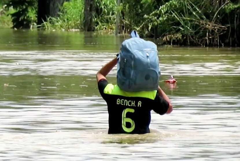 Warga sedsang berjalan melintasi banjir kawasan Bnadung Selatan