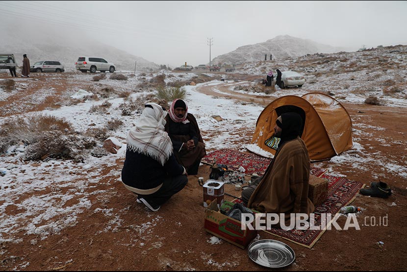 Warga setempat menikmati momoen salju turun di Provinsi Tabuk, Saudi Arabia, Selasa (25/2).
