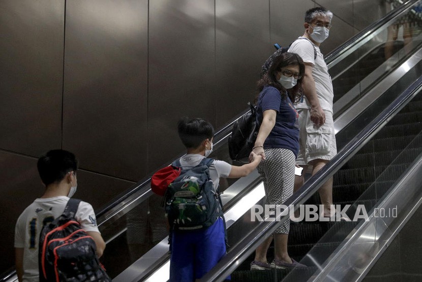 Warga Singapura memakai masker saat menaiki eskalator di dalam stasiun kereta api di Singapura, Rabu (29/1/2020). Tujuh orang berasal dari Wuhan, Cina telah dinyatakan positif terkena virus corona di Singapura.