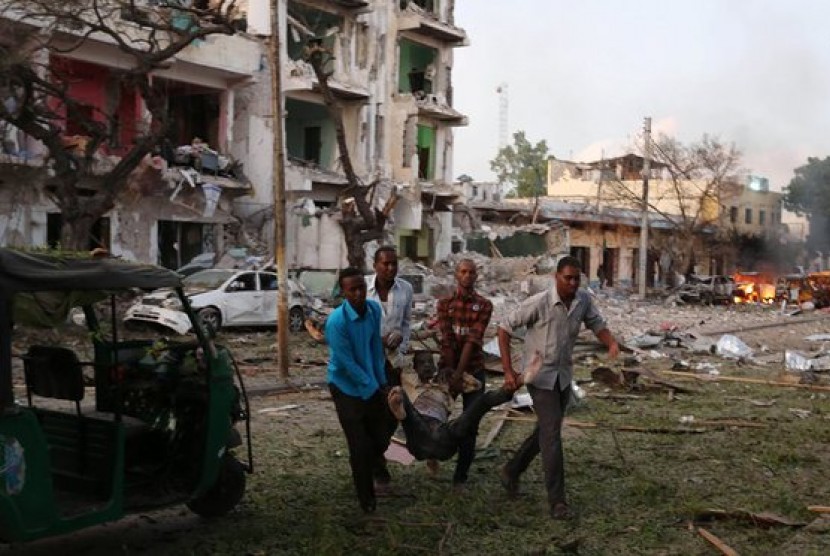 Warga sipil mengevakuasi seorang pria yang terluka akibat pengeboman di Mogadishu, Somalia.