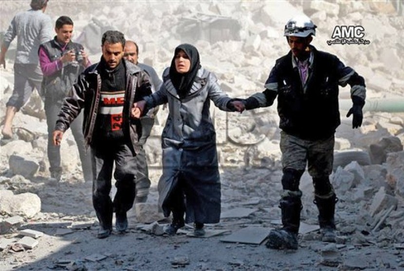  Warga Suriah membantu seorang wanita yang selamat dari ledakan bom di kawasan Masaken Hanano, dekat Aleppo, Suriah.