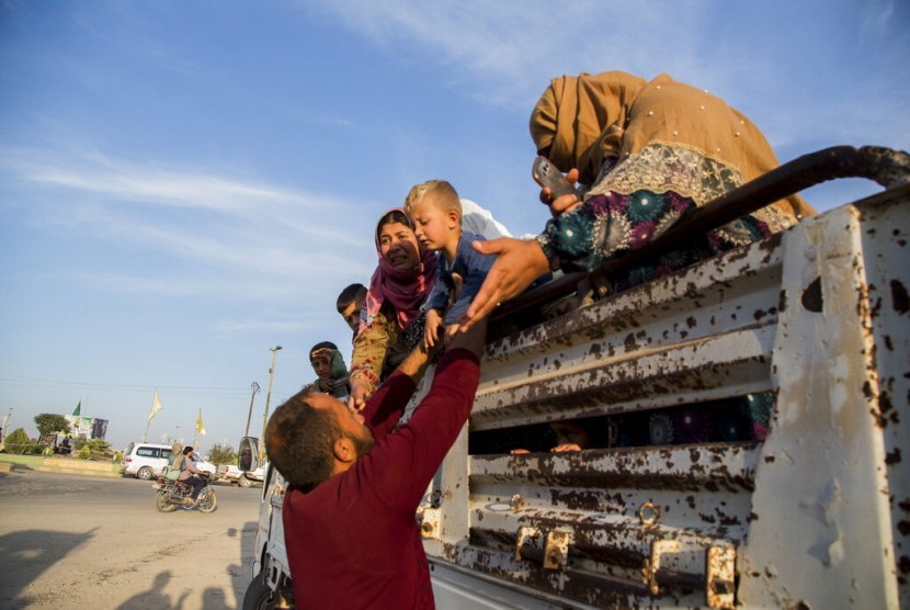 Warga Suriah menyelamatkan diri dari pasukan Turki tiba di Kota Tal Tamr di utara Suriah, Senin (14/10).