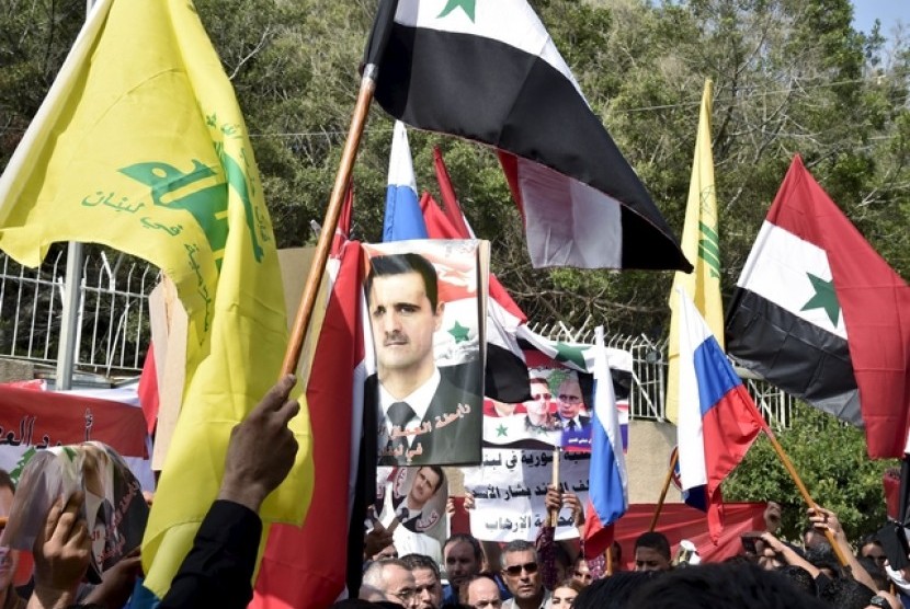 Warga Suriah yang tinggal di Lebanon mengangkat bendera dan foto pemimpin Lebanon. Mereka berterima kasih atas dukungan Lebanon juga Rusia yang mengintervensi Suriah.