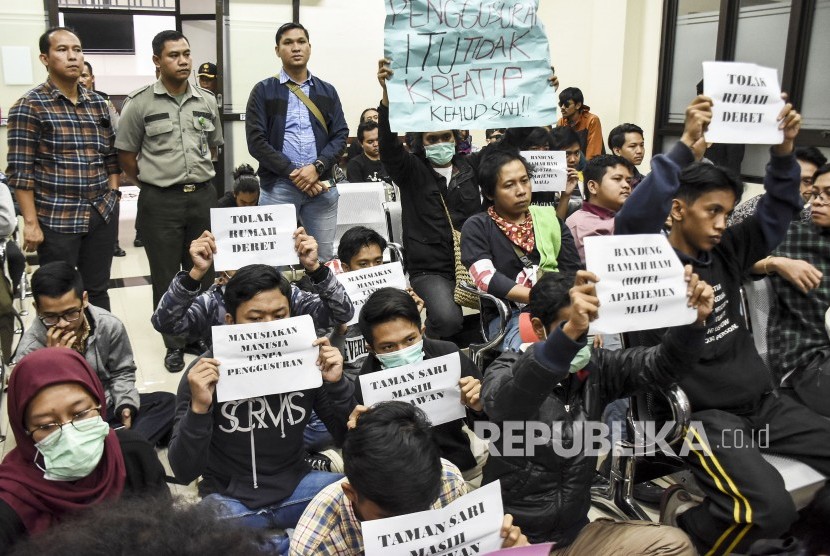 Warga Tamansari korban penggusuran bersama aktivis yang tergabung dalam Tamansari Melawan memegang poster saat menyaksikan jalannya persidangan di Pengadilan Tata Usaha Negara (PTUN) Badung, Jalan Diponegoro, Kota Bandung, Kamis (19/12).