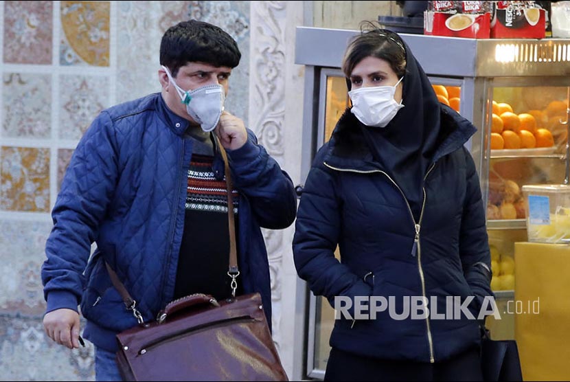 Warga Teheran Iran melintasi jalanan kota menggunakan masker setelah pandemi virus corona di negara tersebut.