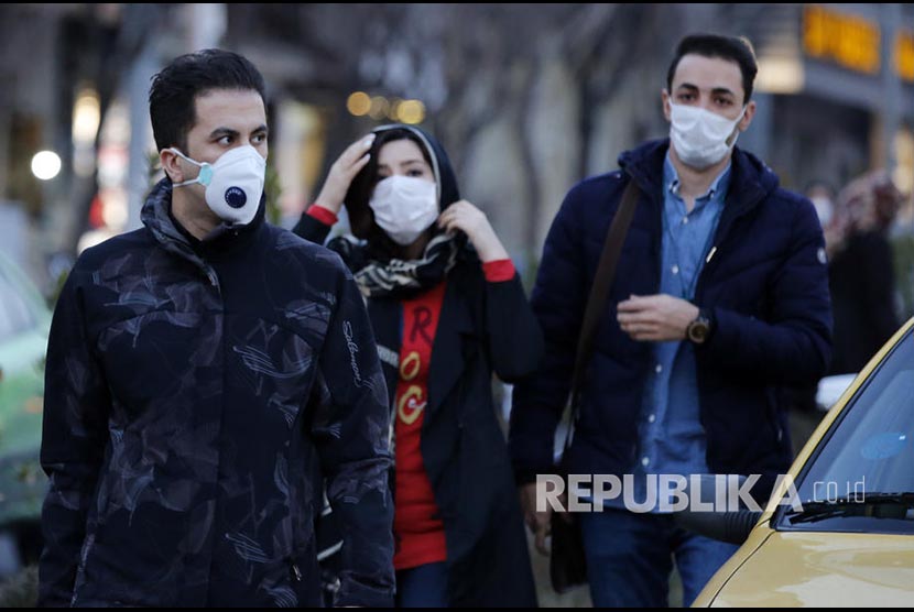 Warga Teheran Iran melintasi jalanan kota menggunakan masker, Sabtu (22/2). 