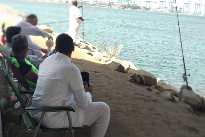Warga tempatan berbincang sambil memancing dengan  latar pelabuhan peti kemas Jeddah, Kamis (2/8). Pelabuhan tersebut dulunya lokasi berlabuh kapal-kapal yang membawa jamaah haji asal Indonesia.
