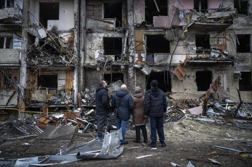 Warga tengah melihat gedung yang hancur akibat serangan roket di Kyiv, Ukraina.