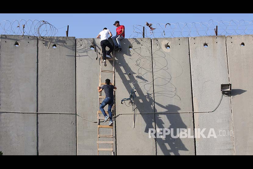 Warga Tepi Barat Palestina menaiki tangga untuk menlintasi tembok pemisah yang dipasang Israel untuk shalat jumat di Kompleks Al Aqsa, Jumat (8/6). Mereka dilarang memasuki Yerusalem berdasar batas umur minimal yang boleh memasuki Al Aqsa. 