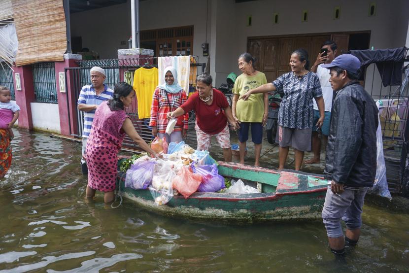 Warga terdampak banjir berbelanja di pedagang sayuran keliling yang menggunakan perahu di Pekalongan, Jawa Tengah, Senin (22/2/2021). Sejak banjir menggenangi Kota Pekalongan, pedagang berinisiatif berjualan menggunakan perahu untuk memudahkan akses melewati banjir. 