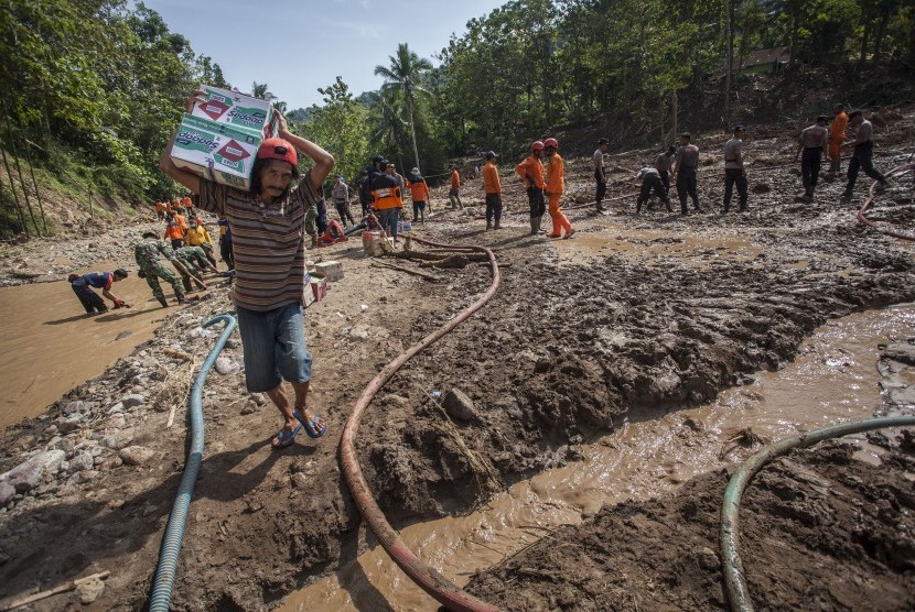 Warga terdampak tanah longsor membawa bantuan logistikmelintasi kawasan bencana longsor di Donorati, Purworejo, Jawa Tengah (Jateng), Selasa (22/6).