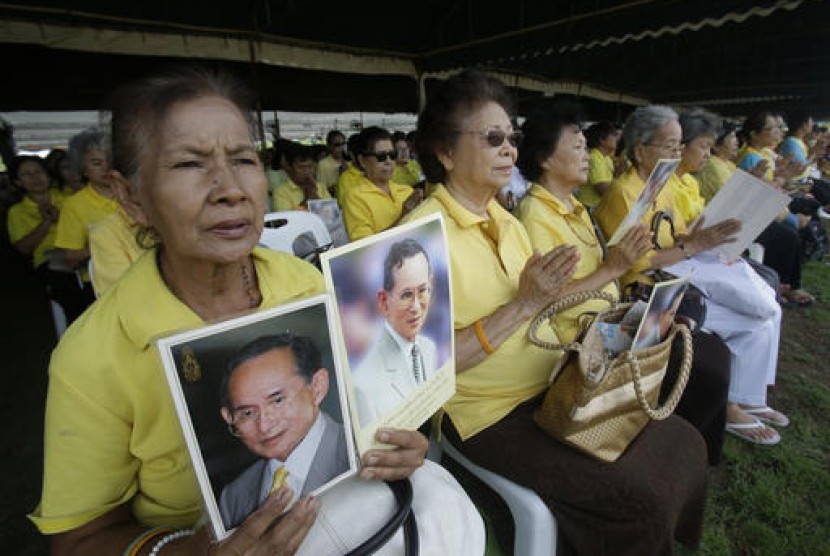 Warga Thailand memegang foto Raja Bhumibol Adulyadejsaat do bersama di luar Istana untuk merayakan ulang tahun ke-70 raja, Kamis, 9 Juni 2016.