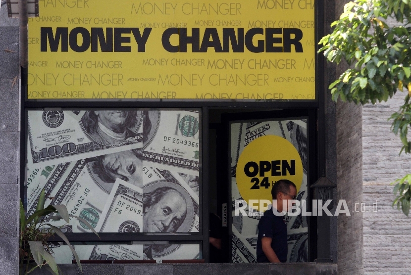 Warga usai melakukan penukaran mata uang asing di sebuah money changer.