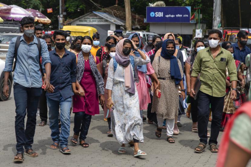 Warga yang mengenakan masker wajah menyeberang jalan di Kochi, negara bagian Kerala, India, Jumat, 8 Juli 2022. India akan melampaui China sebagai negara terpadat di dunia pada 2023.
