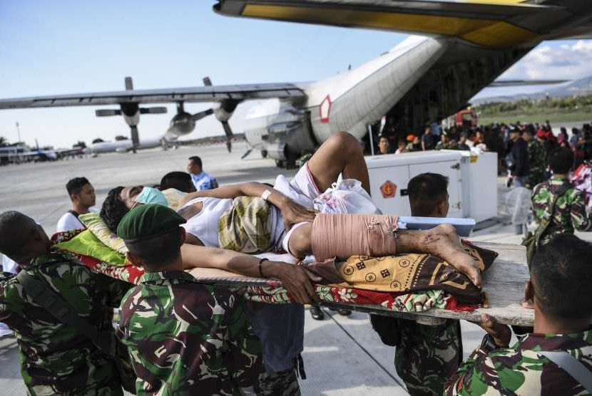 Warga yang terluka digotong personel TNI untuk dievakusi dengan pesawat Hercules di Bandara Mutiara Sis Al Jufri Palu, Sulawesi Tengah, Minggu (30/9).