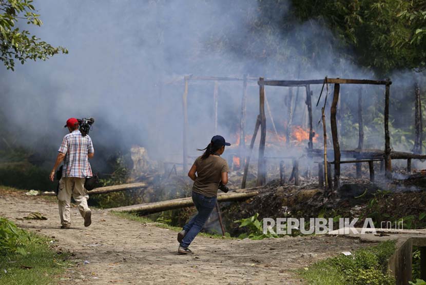  Wartawan berjalan di dekat rumah-rumah yang terbakar di desa Gawdu Thara di kota Maungdaw, Negara Bagian Rakhine, Myanmar barat. Militer Myanmar disebut tak melaporkan kasus pembantaian Rohingya secara utuh. Ilustrasi. 