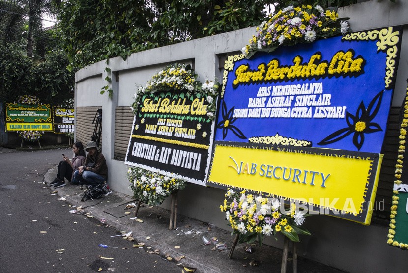 Wartawan duduk di dekat karangan bunga ucapan belasungkawa atas wafatnya aktor Ashraf Sinclair di rumah duka di kawasan Pejaten Barat, Jakarta, Selasa (18/2/2020). Ashraf diduga meninggal akibat serangan jantung.