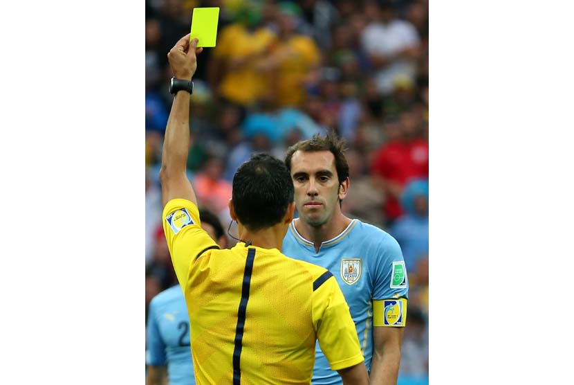 Wasit Carlos Velasco Carballo Spanyol menunjukkan kartu kuning kepada Diego Godin dari Uruguay selama dipertandingan babak penyisihan antara Uruguay dan Inggris di Arena Corinthians di Sao Paulo, Brasil, Kamis (19/6).   (EPA/ Diego Azubel).