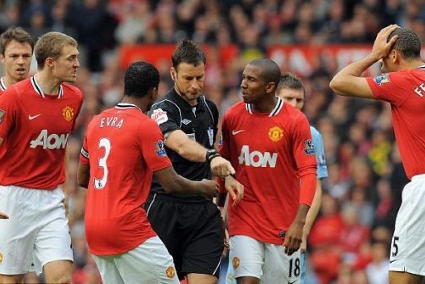 Wasit Mark Clattenburg (tengah) dikerubungi pemain Manchester United yang memprotes keputusan kartu merah Jonny Evans. (ilustrasi)