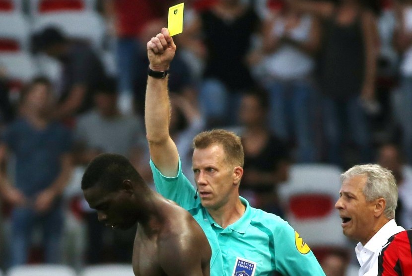 Wasit memberikan kartu kuning kedua kepada striker Nice, Mario Balotelli (kiri) pada laga Ligue 1 lawan Lorient, Ahad (2/10). Laga di stadion Allianz Riviera itu berakhir kemenangan untuk Nice, 2-1.