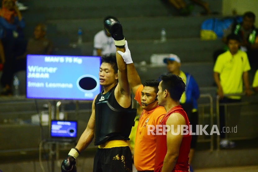 Wasit mengangkat tangan Iman Lesmana asal Jabar (kanan) usai bertarung dengan Syafrizal asal Aceh (kiri) pada petarungan Wushu kelas Sanshou 70 kg putra babak penyisihan, dengan , di Gor Pajajaran, Kota Bandung, Senin (19/9)