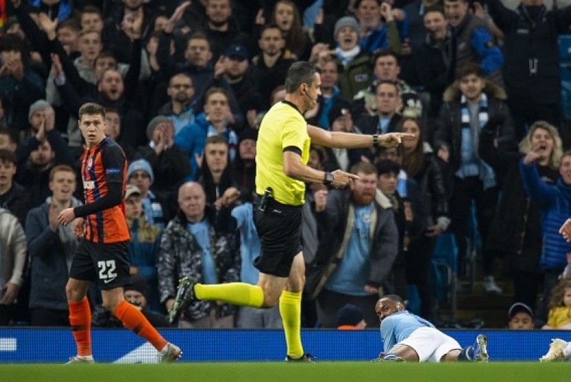 Wasit Viktor Kassai menunjuk titik putih setelah winger Manchester City Raheem Sterling (kanan) terjatuh di kotak penalti Shakhtar Donetsk.