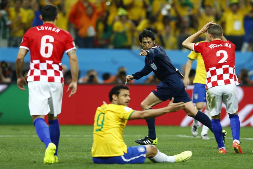 Wasit Yuichi Nishimura (tengah) dari Jepang, untuk memberikan hukuman selama Piala Dunia 2014 pertandingan pembukaan antara Brasil dan Kroasia di arena Corinthians di Sao Paulo 13 Juni 2014.