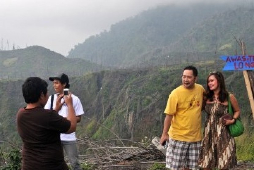 WISATA PASCA ERUPSI MERAPI. Sepasang wisatawan lokal berfoto di kawasan Kinahrejo, DIY, Sabtu (23/4), yang rusak akibat erupsi Gunung Merapi beberapa waktu lalu. Beberapa lokasi di kaki Gunung Merapi yang rusak terkena erupsi gunung tersebut menjadi salah 