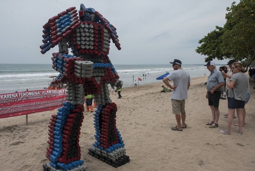 Wisatawan asing melihat boneka robot berbahan botol plastik bekas di Pantai Kuta, Rabu (27/12). 