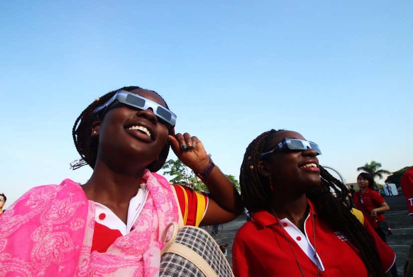 Wisatawan asing menggunakan kacamata gerhana saat menyaksikan Gerhana Matahari Total (GMT) di Planetarium, Jakarta, Rabu (9/3).