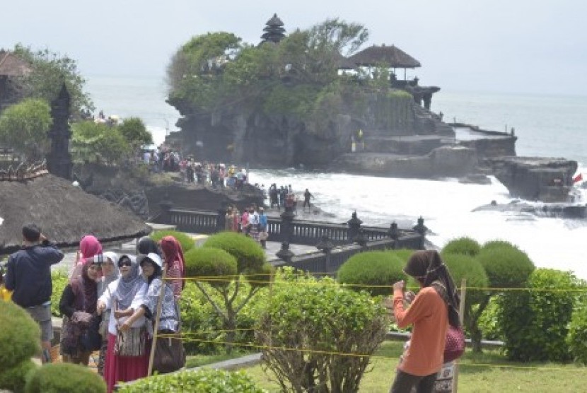 Wisatawan berfoto bersama dengan latar Pura Tanah Lot di Kabupaten Tabanan, Bali, Sabtu (26/12). 
