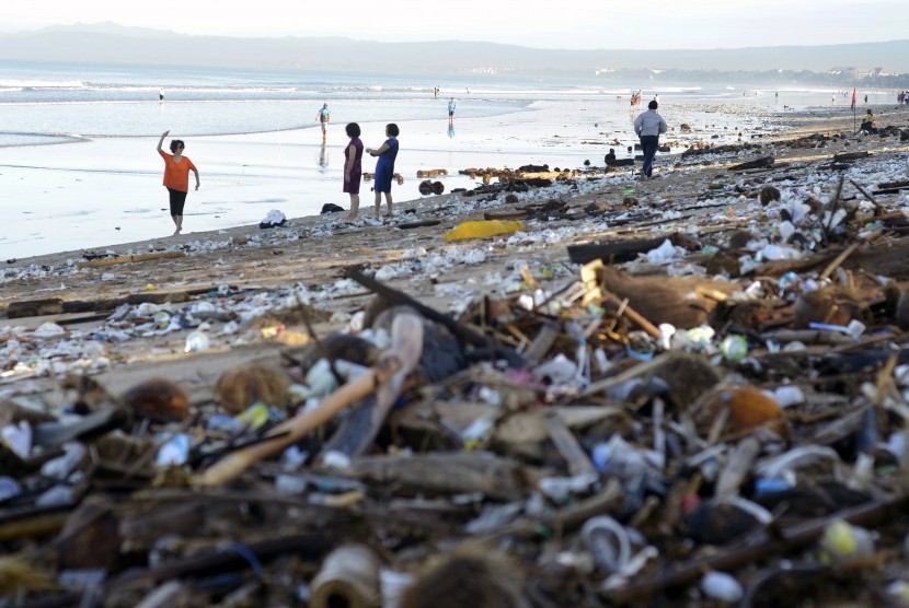 Wisatawan berfoto di antara tumpukan sampah yang terdampar di Pantai Kuta, Bali, Senin (15/2).