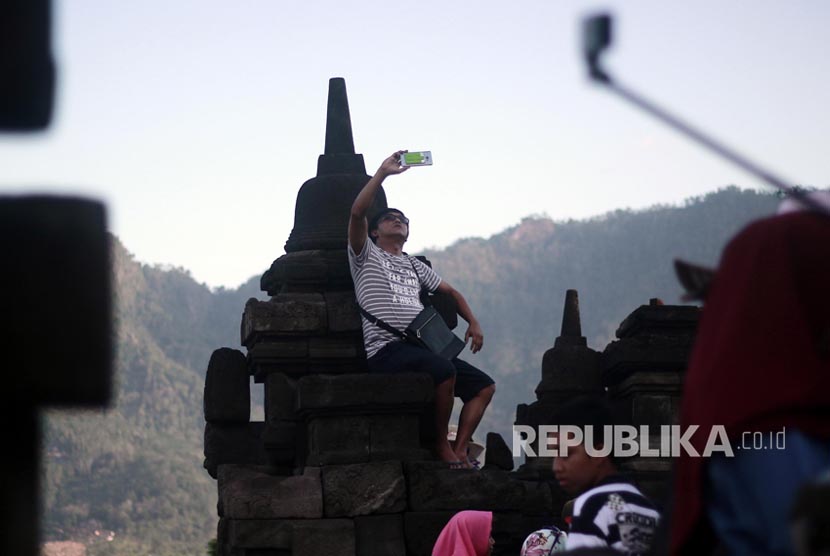 Wisatawan berfoto diatas dinding candi walaupun berbahaya, wisatawan Candi Borobudur, Magelang Jawa Tengah untuk mengisi waktu libu Idul Fitri tercatat Rabu (28/7).