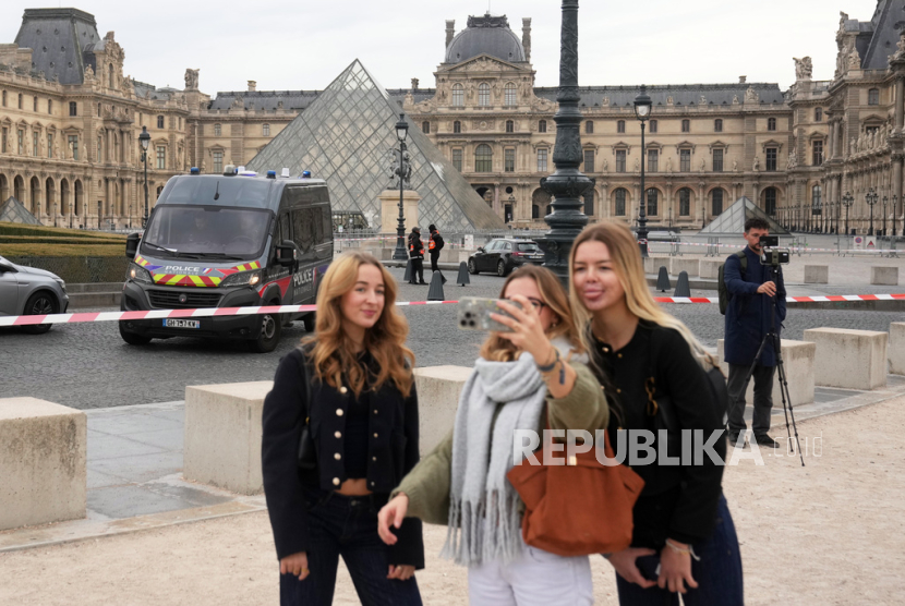 Wisatawan berfoto selfie di halaman Museum Louvre yang ditutup setelah terjadi perampokan pada Ahad, 19 Oktober 2025, di Paris. 