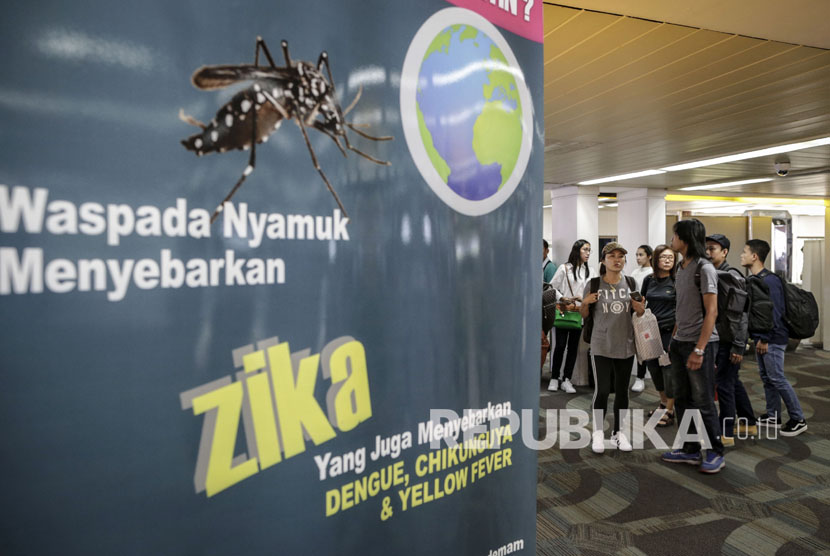  wisatawan berjalan melewati sebuah banner himbauan kewaspadaan terhadap virus Zika di Bandara Internasional Soekarno-Hatta di Tangerang.