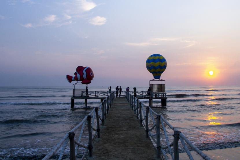 Wisatawan berswafoto sambil menikmati matahari terbit di Pantai Tanjung Pakis, Desa Pakis Jaya, Karawang, Jawa Barat, (ilustrasi).