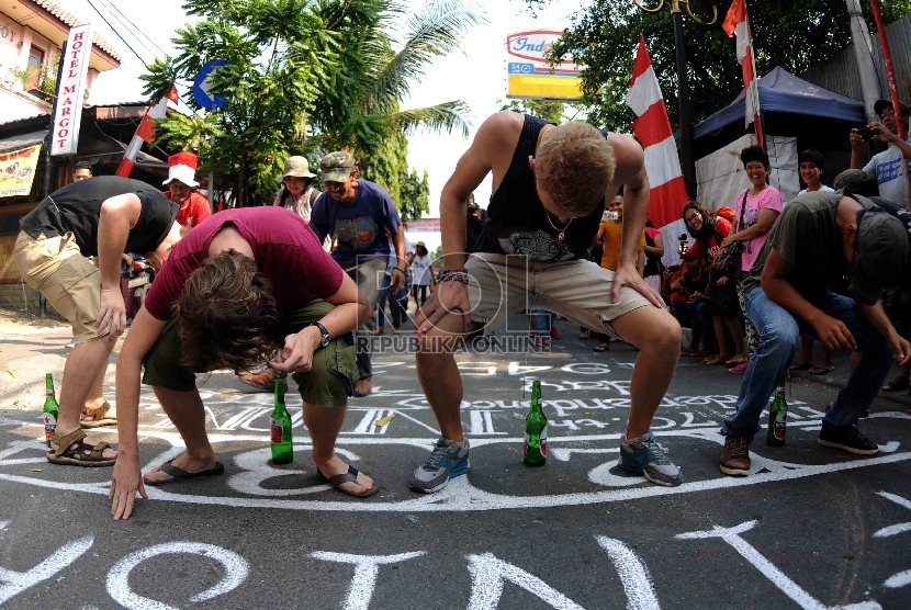  Wisatawan dari mancanegara mengikuti lomba memasukan paku ke dalam botol dalam lomba 17 Agustus di Jalan Jaksa, Jakarta, Senin (17/8).   (Republika/Agung Supriyanto)