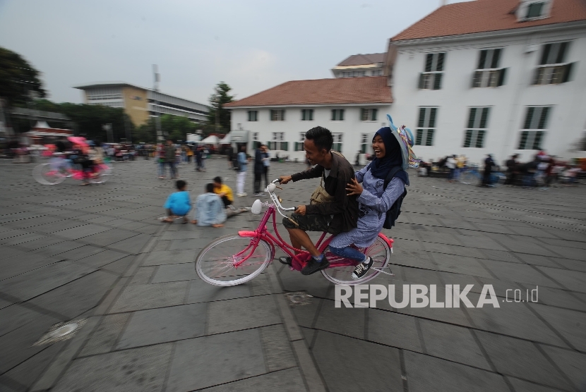 Wisatawan Kota Tua mengendarai sepeda, Jakarta, Ahad (24/9).
