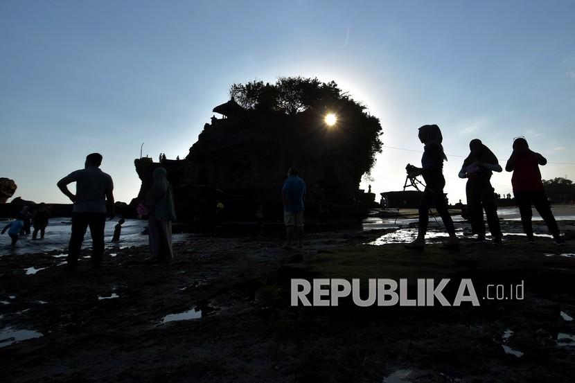 Wisatawan lokal menikmati suasana hari di Pantai Tanah Lot, Tabanan, Bali.